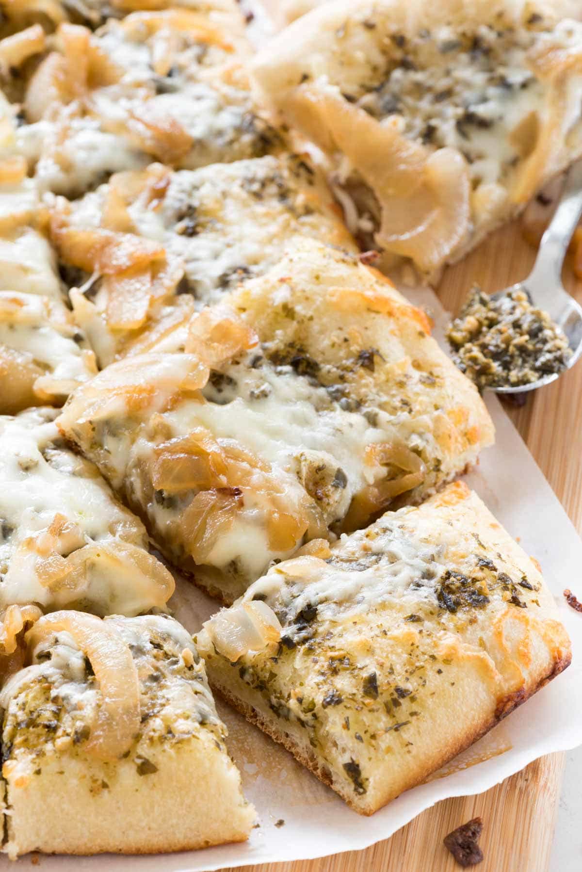 Caramelized Onion Pesto Flatbread Pizza - this EASY 4 ingredient pizza recipe is the perfect appetizer. Pesto, caramelized onions, and mozzarella baked onto a pizza crust - every time I make this people rave about it!