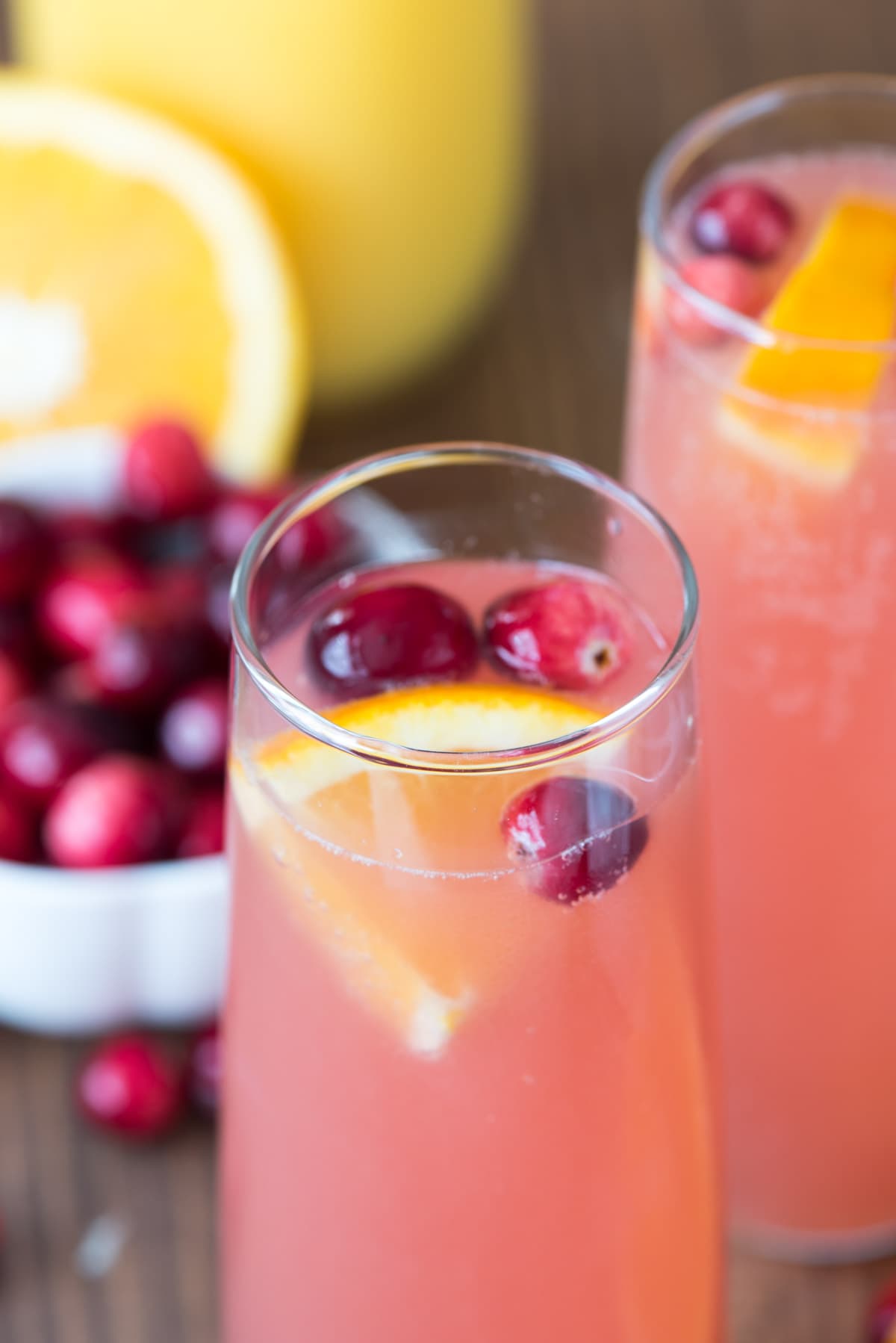 Two Cranberry Orange Mimosas garnished with sliced oranges and cherries.