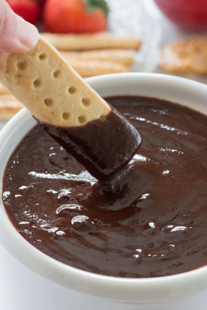cookie dipping into fondue pot with chocolate fondue