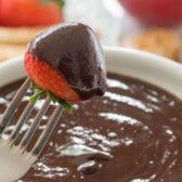 fork dipping strawberry in chocolate fondue with words on photo