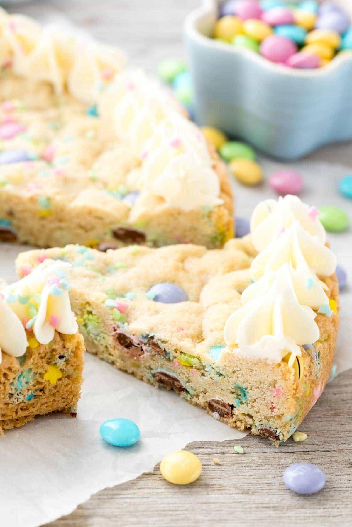 Easter Sugar Cookie Cake - this easy sugar cookie recipe is filled with spring M&Ms and sprinkles and baked in a cake pan. Make an easy frosting and you have the perfect spring cookie cake!