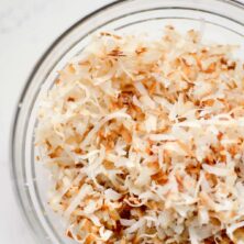 bowl of toasted coconut in a glass bowl with writing
