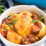 Easy Cheesy Chili Biscuit Bakein a white bowl - this easy weeknight dinner recipe has just 5 ingredients! Chili is topped with vegetables, biscuits, and cheese then baked up for a delicious comfort food meal.