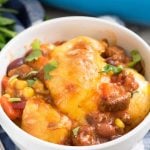 Easy Cheesy Chili Biscuit Bakein a white bowl - this easy weeknight dinner recipe has just 5 ingredients! Chili is topped with vegetables, biscuits, and cheese then baked up for a delicious comfort food meal.