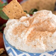 Churro Cheesecake Dip in a bowl with graham crackers to dip - an easy way to make no-bake cheesecake dip full of cinnamon sugar churro flavor! This is the perfect party dip or an easy dessert recipe.