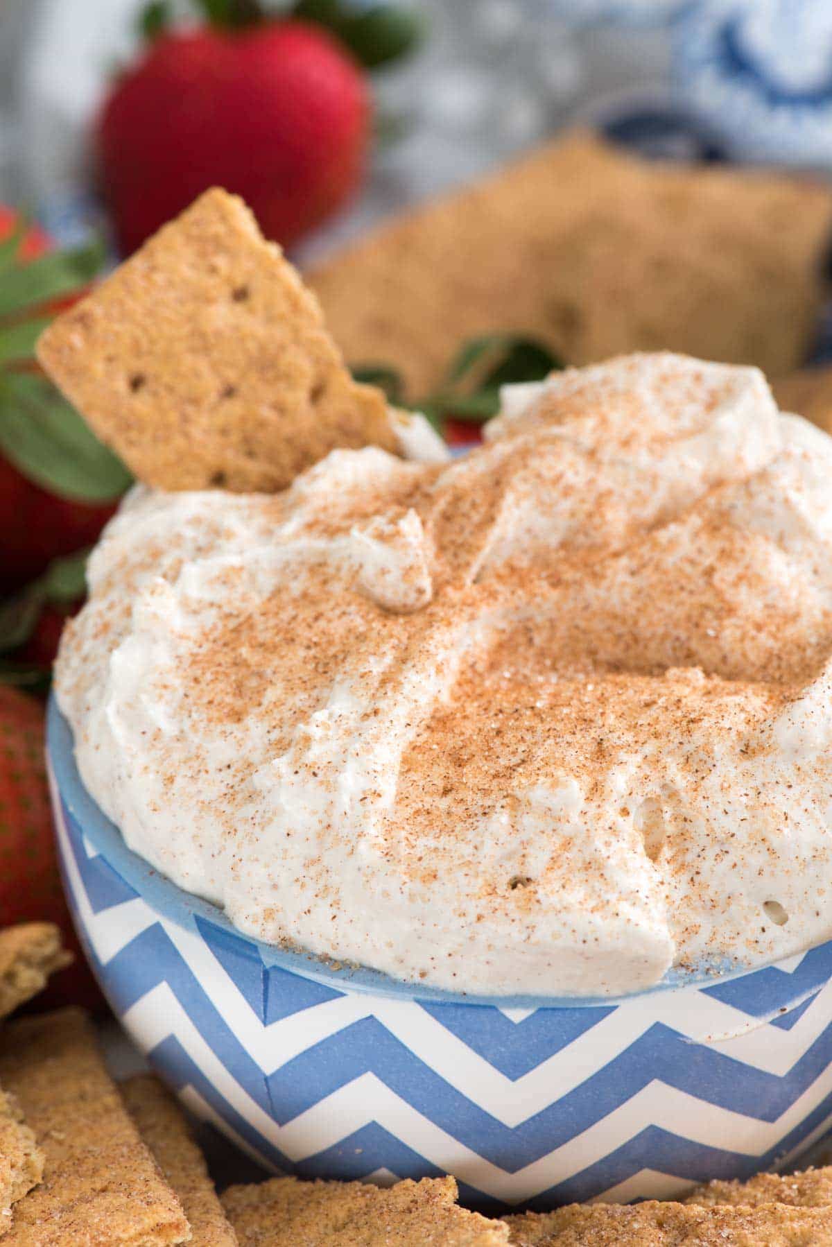 Churro Cheesecake Dip in a bowl with graham crackers to dip - an easy way to make no-bake cheesecake dip full of cinnamon sugar churro flavor! This is the perfect party dip or an easy dessert recipe.