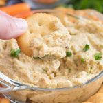 Roasted Garlic Lentil Dip in a glass bowl with a cracker to dip