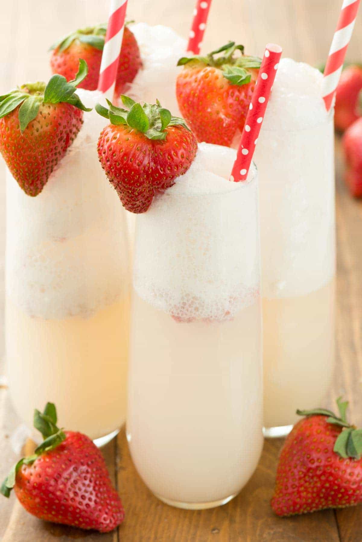 Four Strawberry Shortcake Mimosa with straws garnished with fresh strawberries. 