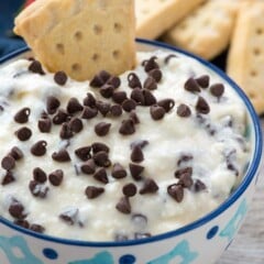 Shortbread triangle dipped in a bowl of Cannoli Cream Dip.