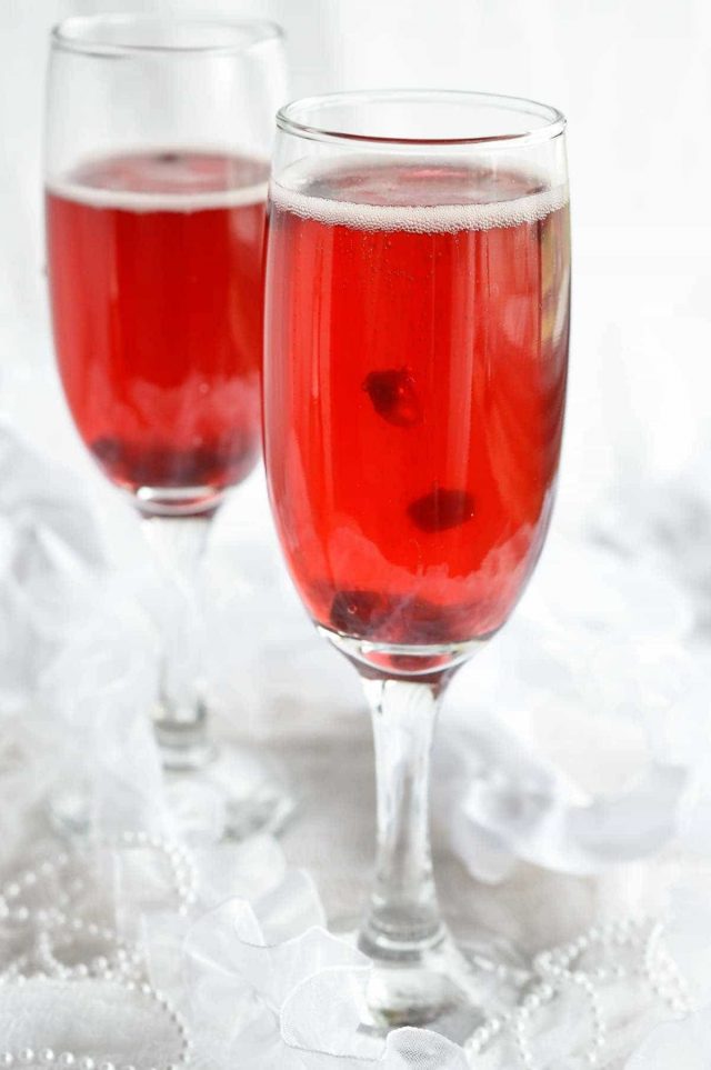 Two champagne glasses of Pomegranate Mimosas.