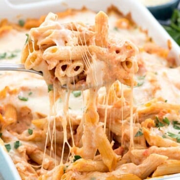 Easy Baked Penne Pasta Casserole in a blue casserole dish and a fork full being lifted out of the dish