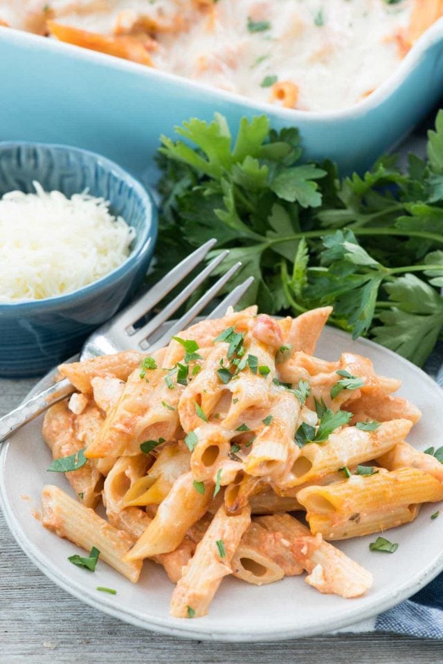 Baked Penne on a small plate with a silver fork with a side of grated cheese.