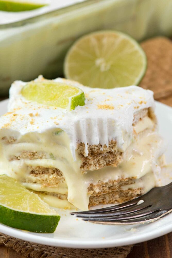 No Bake Key Lime Eclair on a white plate with fork and slices of lime and bite missing