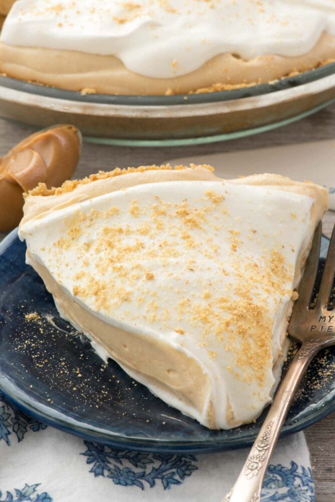 Pie sitting on a blue plate with a fork on wooden board 