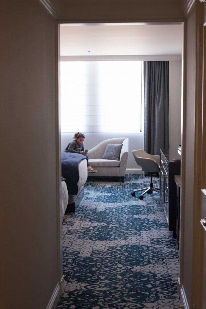 girl sitting on bench looking at phone in hotel room