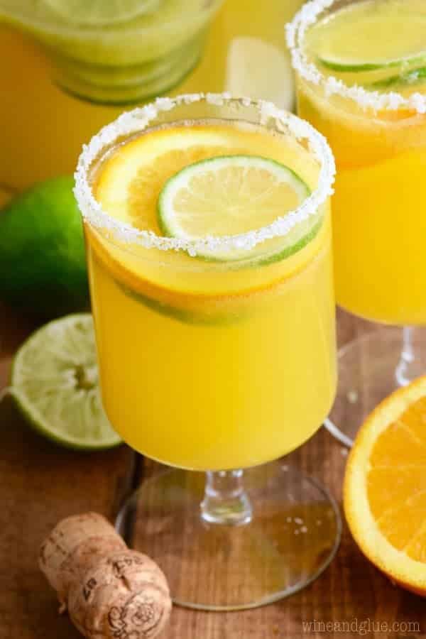 Two Mimosa Margaritas rimmed with salt and garnished with sliced limes and oranges. 