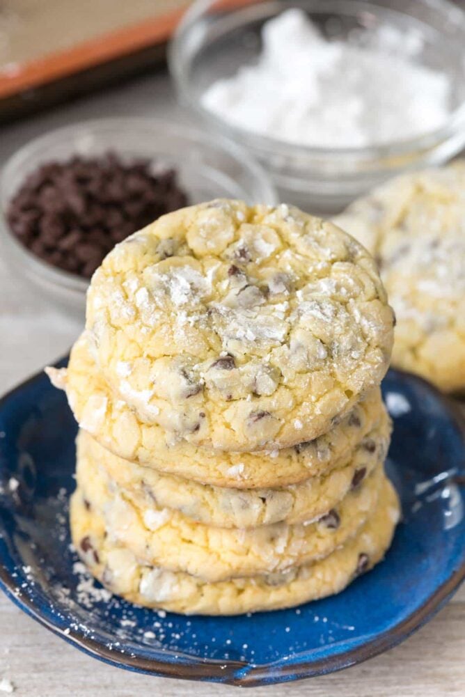 Stack of cookies on a blue plate with chocolate chips and sugar in the background