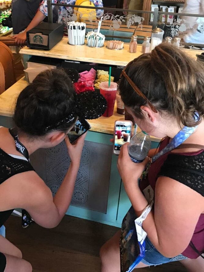 girls taking photos of starbucks drinks in Disneyland Starbucks