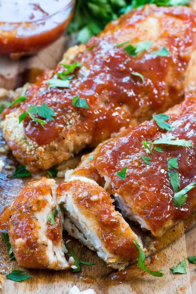 Easy Oven Baked BBQ Chicken sliced on cutting board with BBQ sauce