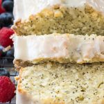 sliced almond poppyseed cake with frosting on rack