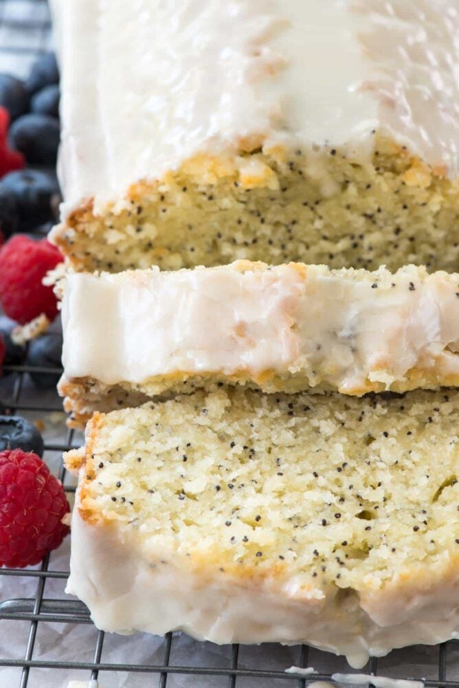 sliced almond poppyseed cake with frosting on rack