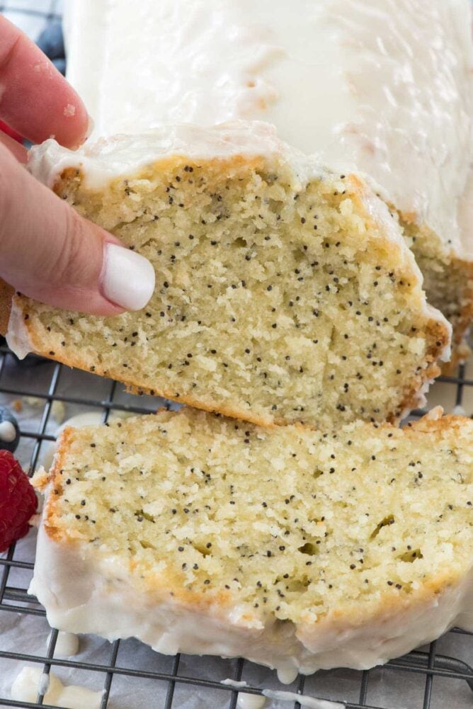 Almond poppyseed bread slice with icing on a wire rack.