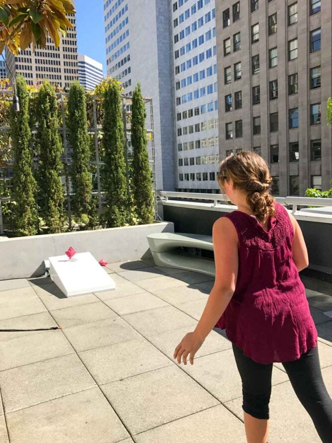 girl playing cornhole on patio