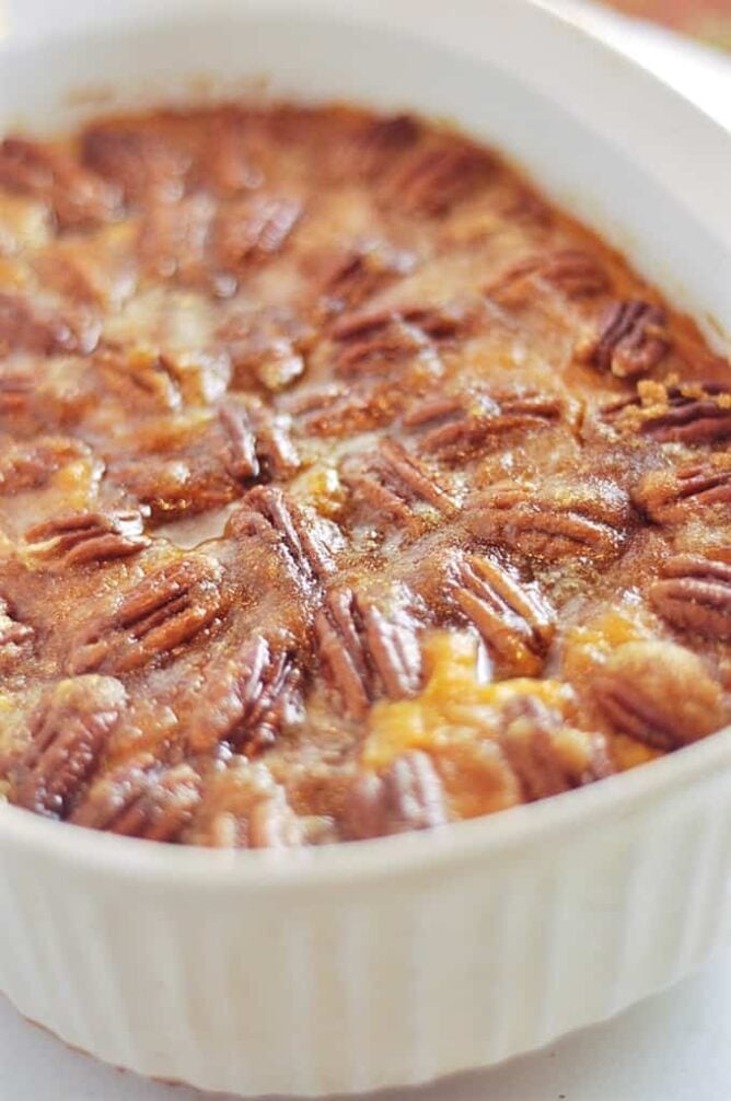 Pecan topped sweet potatoes in a white casserole dish.