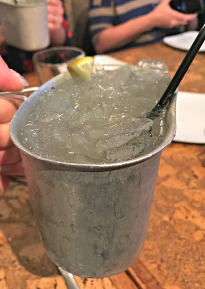 a metal bucket with ice and a drink sitting on a table