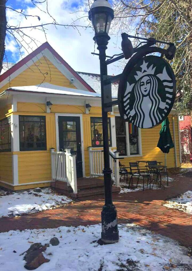 Picture of Starbucks logo and a small yellow starbucks  location in the back