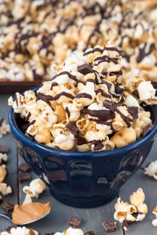 Chocolate Peanut Butter Popcorn in a blue bowl with more popcorn scattered around