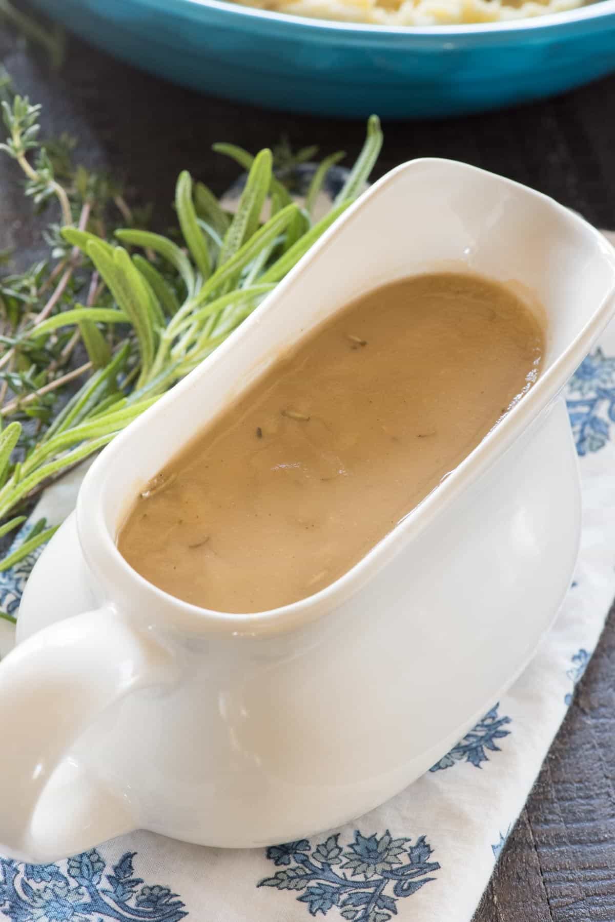 Gravy in a white gravy boat on a blue and white napkin