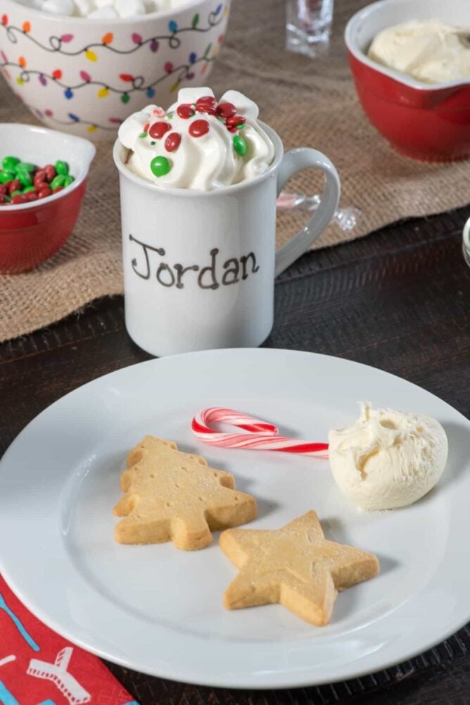 Christmas cookies on a white plate with a mug in the background