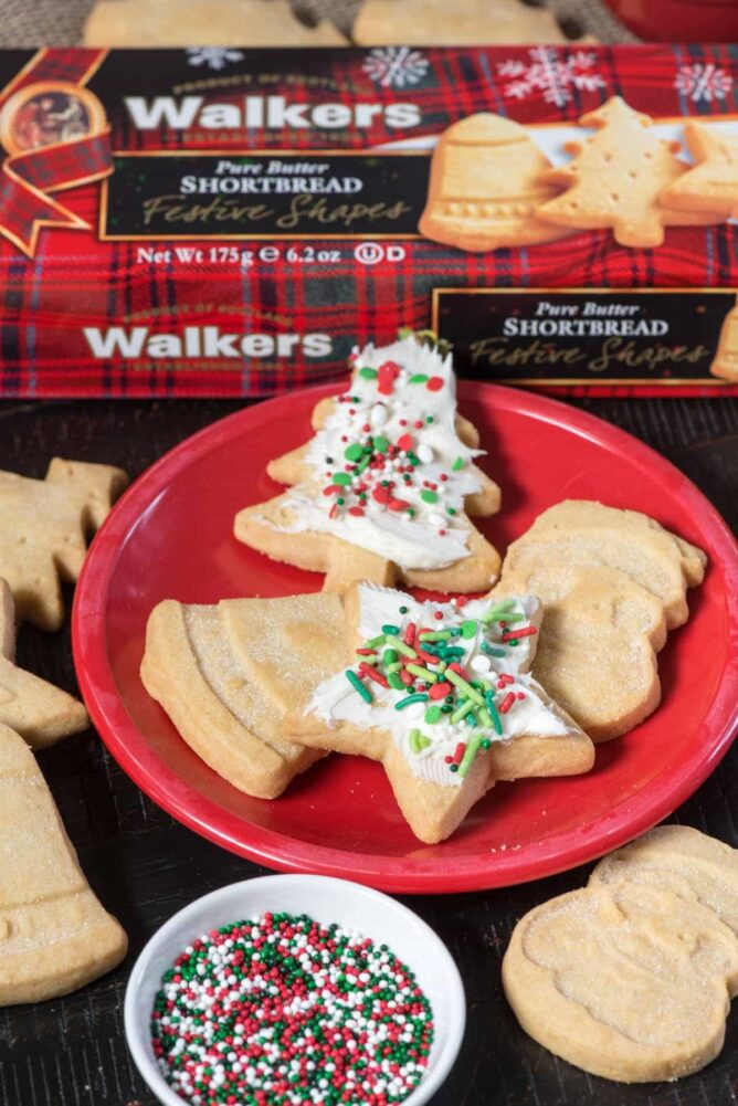 Christmas cookies on a red plate with Walkers Shortbread cookies in the background