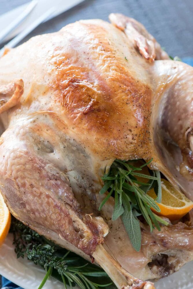 Cooked Turkey on a white platter with herbs