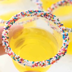 Hand holding lemon jello shot with sprinkles