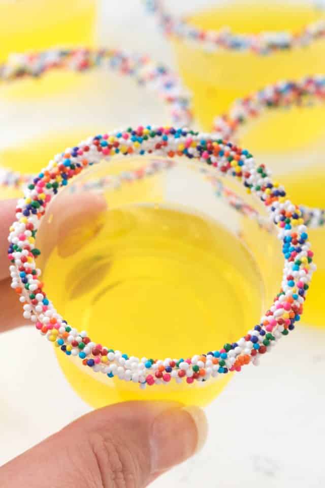 Lemon Cake Jello Shots taste like cake! This classic Jello shot recipe gets a twist with cake vodka and sprinkles for the perfect party shot!