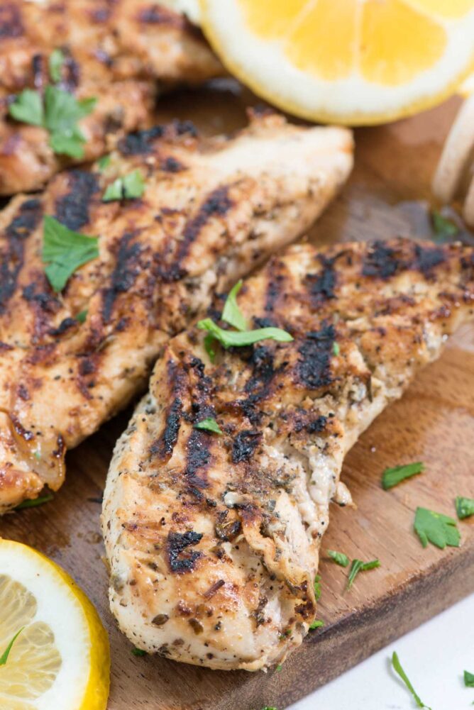  lemon herb chicken on a cutting board with lemon slices