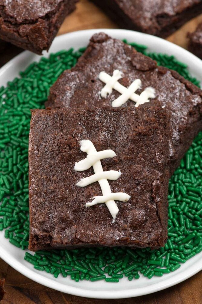 Football brownies surrounded by green sprinkles on a white plate