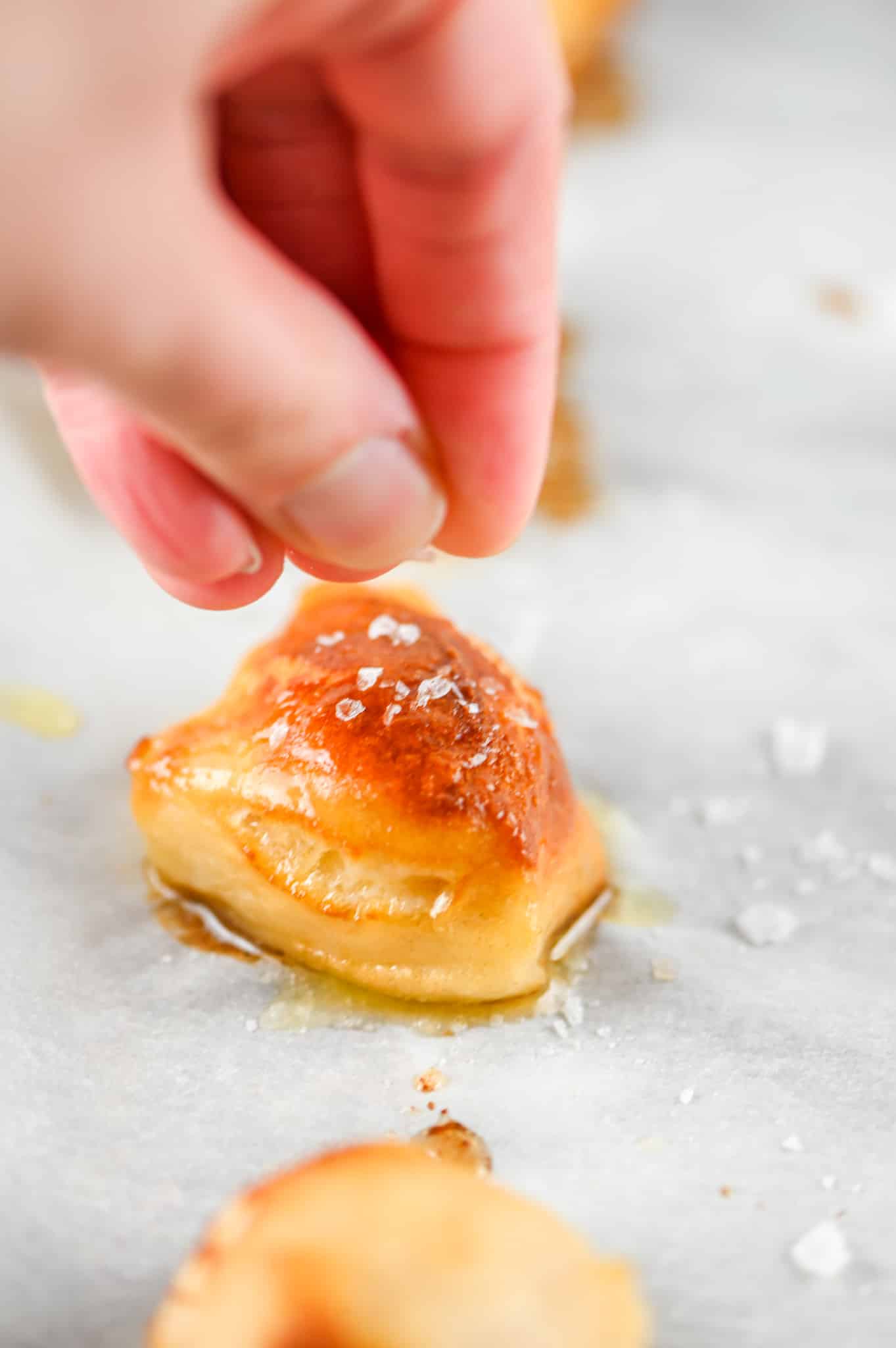 hand sprinkling salt on pretzel bite