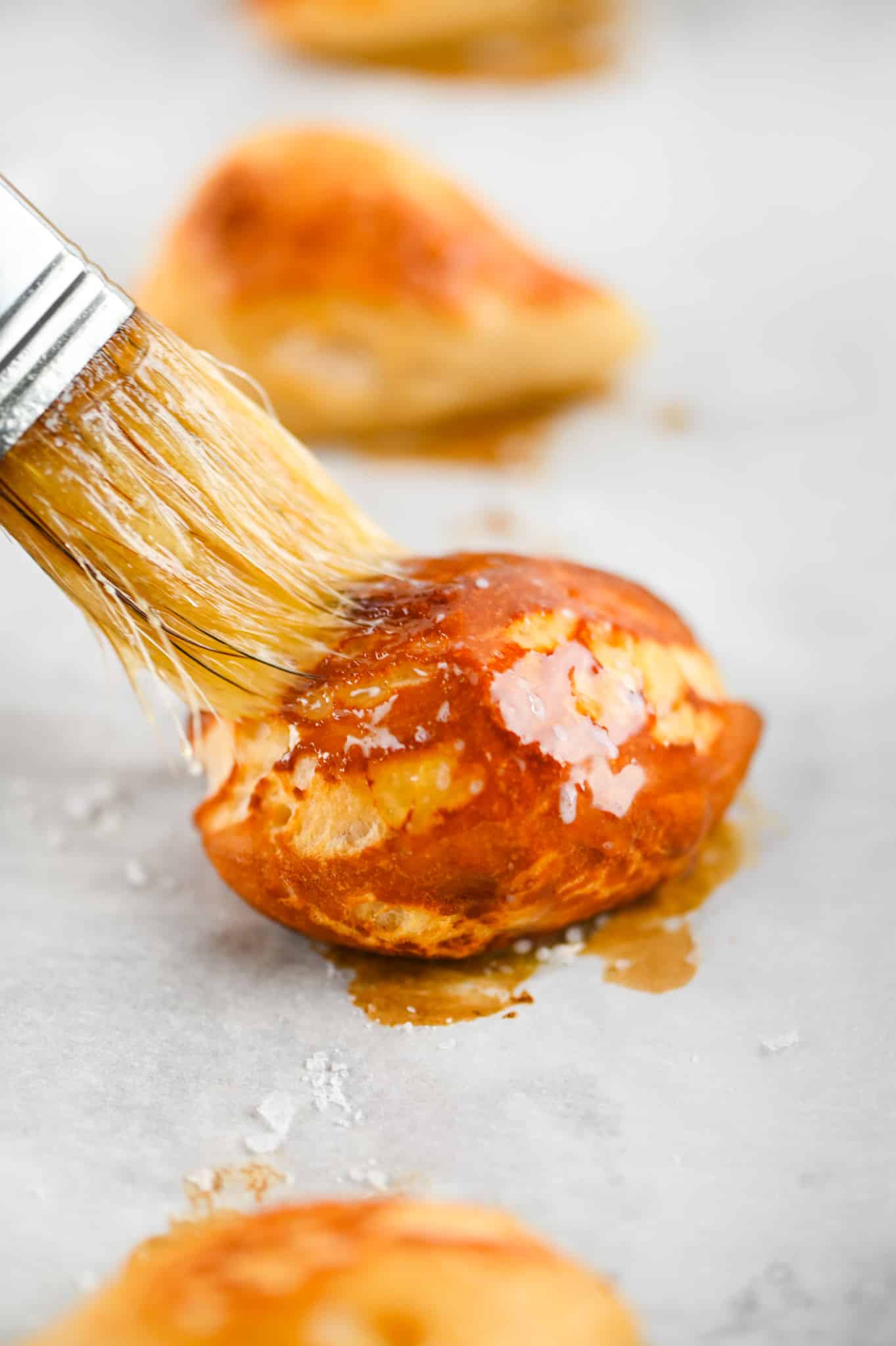 hand brushing butter on pretzel bite