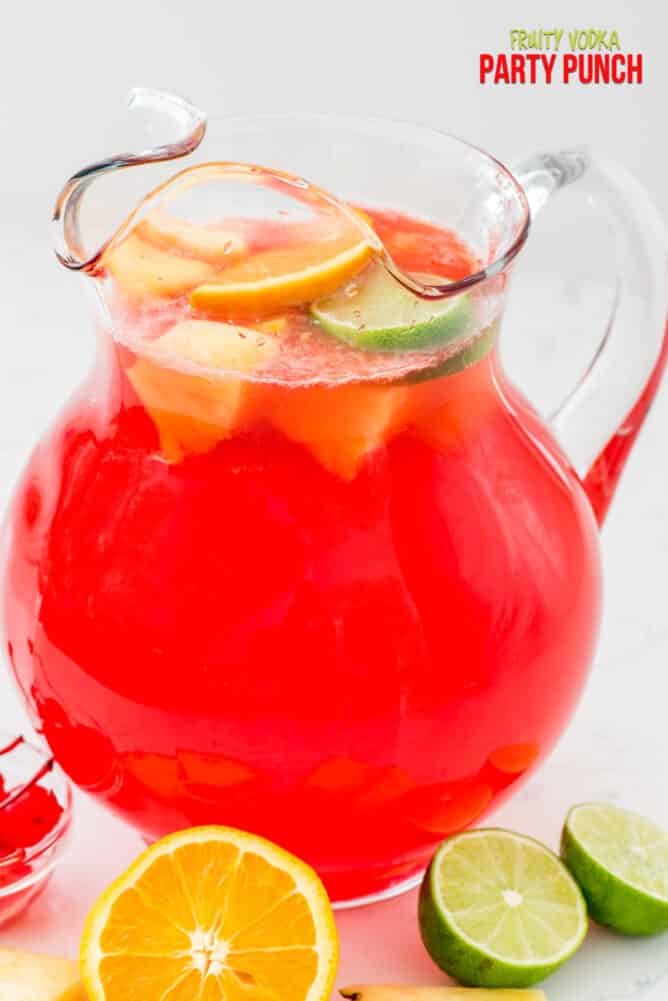 red vodka punch in pitcher with lemons and limes around the pitcher 