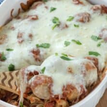 Casserole dish with spoon holding up meatballs and cheese