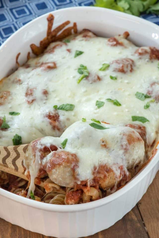 Casserole dish with spoon holding up meatballs and cheese
