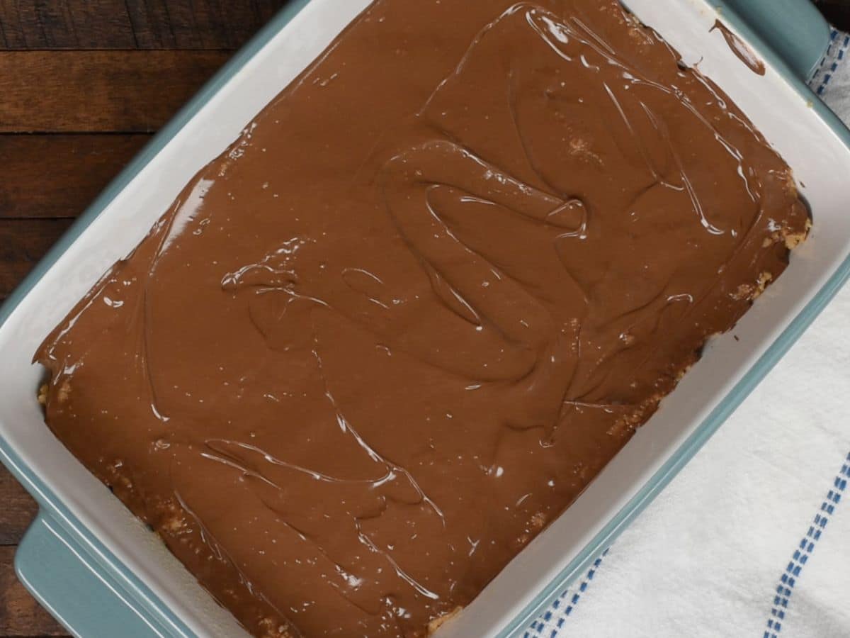 chocolate spread on top peanut butter mixture in pan.