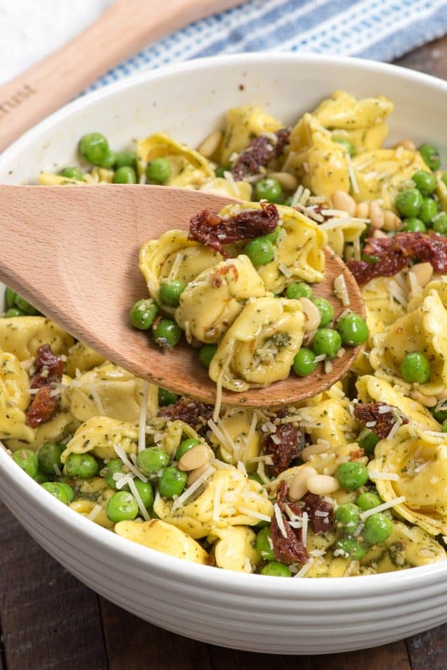 Pesto Tortellini salad on spoon in white bowl