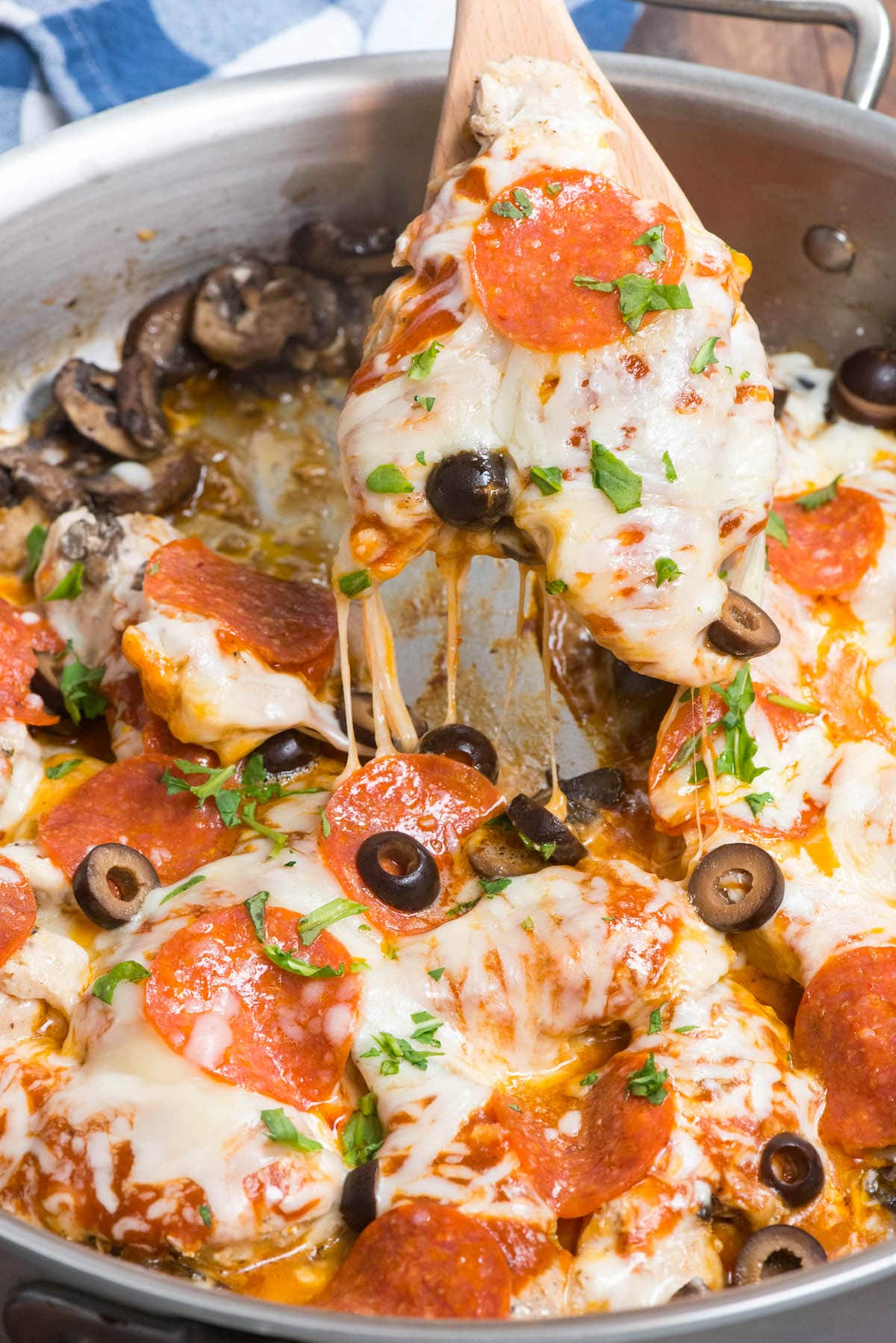 pizza topped chicken in skillet with spoon holding some up