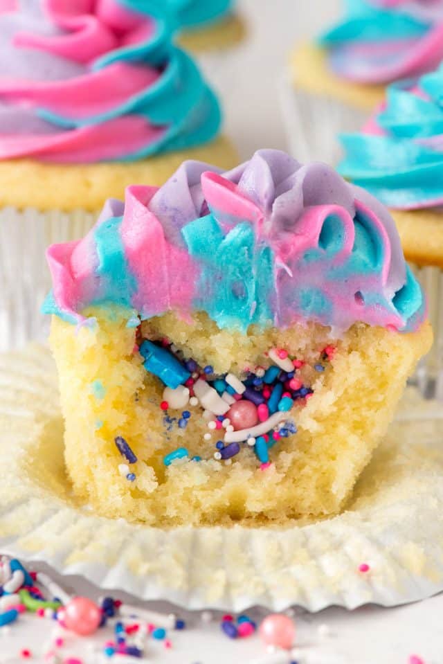 sliced open unicorn cupcake with sprinkles inside