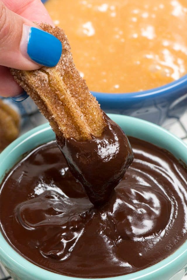 churro being dipped in chocolate ganache