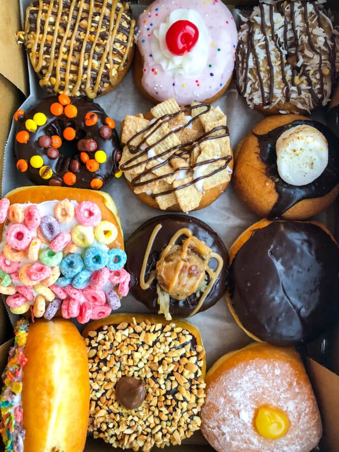 A dozen donuts decorated in many different ways